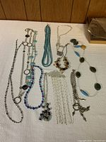Overview of all costume jewelry pieces laid out on white surface showing variety of necklaces and bracelets.