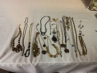 Overview photo of all costume jewelry items laid out on a white fabric background showing necklaces and earrings with various styles and colors.