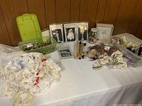 Wide view of lace trims, buttons in containers, craft kits, and ring bearer pillow arranged on white cloth