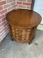 Photo showing full view of the round top wooden drum table with closed cabinet door detailing the raised panel door and metal latch