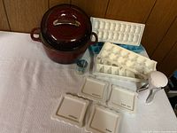 Cast iron pot with lid, ice cube trays, shot glass, and labeled ceramic plates arranged on a table