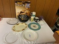 Full view of kitchenware including glass dishes, plates, assorted mugs, and white teapot.