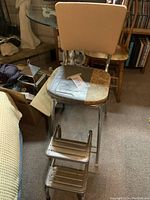 Full view of vintage kitchen stool with square patchwork upholstered seat taped and beige backrest, positioned indoors.