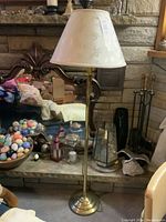 Full view of tall brass floor lamp with white floral fabric shade in living room setting.