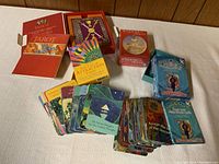 Four oracle and tarot card decks shown with cards spread out on table, boxes open, and one unopened box.