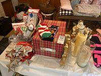 Wide shot showing mixed Christmas decorations including plush toys, gift bags, board game, socks, candle holders and garlands arranged on table