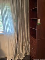 Pair of light blue drapes hanging beside a window, showing length and overall condition