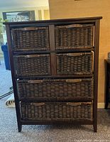 Front view of chest showing six wicker drawers with wooden frame and leather handles