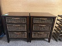 Front view showing two matching wooden chests with three wicker drawers each and wooden handles.