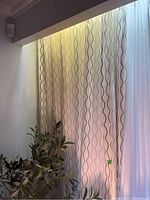 Three IKEA drapes hanging with visible wavy line pattern in a lighted room.