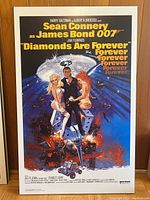 Front view of the mounted Diamonds Are Forever movie poster featuring Sean Connery as James Bond with two women and a diamond motif background