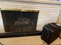 Klipsch soundbar sitting in front of fireplace with subwoofer and remote cord visible on top of subwoofer