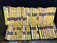 View of approximately 50 Nancy Drew hardcover books lined up showing spines with yellow color, numbering and Carolyn Keene authored series.