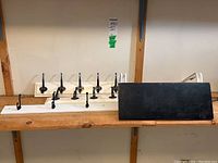 Three Ikea wall-mounted coat racks with black hooks and one black wall-mounted shelf with white brackets, displayed on a wooden surface against a wall.