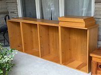 Four oak veneer shelving units displayed in a row with detachable shelves stacked on top.