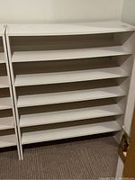 Front view of three white laminate shoe racks side by side, showing multiple shelves.