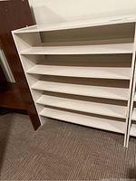 Front view of one white laminate shoe rack showing 5 horizontal shelves with open sides.