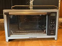 Full frontal view of the Hamilton Beach toaster oven showcasing the glass door, silver body, and handle on top.