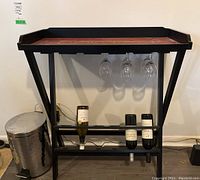 Front view of wooden wine rack with bottles and glasses hung underneath the shelf.