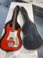 Full view of red electric guitar inside open black hardshell case