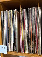 Shelf with two rows of vinyl records showing album spines and edges, confirming quantity and condition of lot.