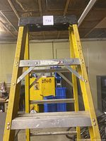 Full front view of the yellow aluminum step ladder showing the 7 steps and top black cap with wear.