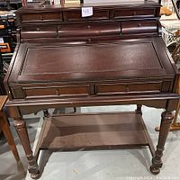 Front view of Coaster Fine Furniture secretary desk showing top drawers, curved roll-top drawers, and lower shelf.