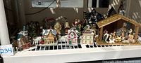 Photo of multiple ceramic holiday village buildings and Nativity scene arranged in a row showing their detailed design and festive decoration.
