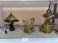Photo showing both lamps side by side on a shelf: the brass tea pot lamp on the right and the Art Deco small accent lamp on the left.