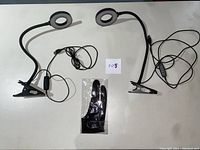 Two USB powered LED clip desk lights with flexible arms and clips, and one black XP-Pen drawing glove in plastic bag laid out on a flat surface.