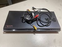 Top view of the LG Blu-ray player showing the AV cables coiled on top and power cord.