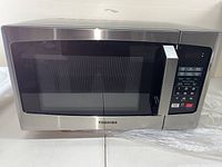 Front view of Toshiba microwave oven showing stainless steel door with black trim and digital keypad on the right side.