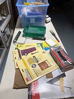 Various painting supplies including sanding sheets, paint rollers with trays, brushes, and tools arranged on a table.