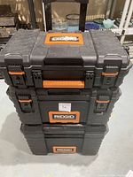Stack of three RIDGID modular rolling tool boxes showing front and side latches, handles, and logos.