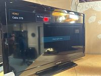 Front of Samsung flatscreen TV powered on showing HDMI2 and Cable STB input labels with 'No Time Information' message and 'Check signal cable.' message on screen.