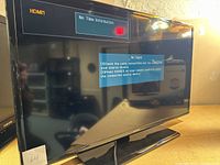 Front view of Samsung flatscreen TV powered on, HDMI1 input selected, displaying 'No Time Information' and 'No Signal' message, indicating TV screen and display functional but untested for other operation.