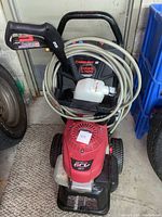 Front view showing red Honda engine cover, wheels and coiled beige hose