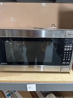 Front view of Panasonic microwave oven showing stainless steel body, black door window, and complete keypad on the right side.