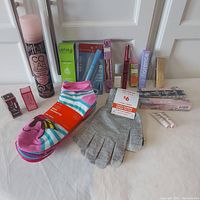 Photo showing all items including dry shampoo, deodorant, lip products, perfumes, socks, and gloves arranged on a white surface with background door.