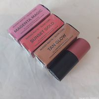 Four NudeStix Matte + Glow Core All Over Face Blush sticks in boxes showing colors Magenta Magic, Sunset Gold, and Tan Glow, one cap removed.