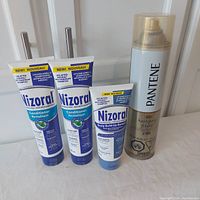 Photo of 2 tubes of Nizoral Conditioner, 1 tube of Nizoral Scalp Build-up Remover, and 1 can of Pantene Hairspray on a white surface.
