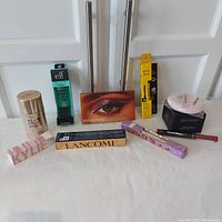 Photo of the full lot showing all makeup products boxed and arranged on a white surface in front of white cabinet doors.