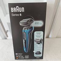 Front view of sealed Braun Series 6 Model 6020s electric shaver box showing blue and black shaver with SensoFlex head and features.