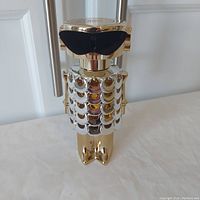 Front view of the Paco Rabanne Fame tester bottle showing gold metallic owl-shaped design with scale details and black sunglasses.