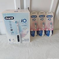Full view of the Oral-B iO Series 5 toothbrush box alongside three packs of replacement brush heads, all sealed.
