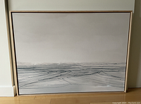 Full front view of the Dan Hobday abstract landscape canvas artwork in blond wood floater frame showing the entire framed canvas on floor against white wall.