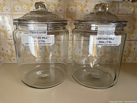 Two clear glass Anchor Hocking Heritage Hill jars side by side with lids, showing size and design.