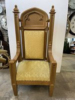 Full front view of pulpit chair with arms showing carved wooden back and yellow fabric upholstery