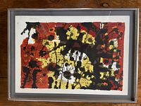 Framed abstract lithograph with red, yellow, black, and white colors, signed and numbered.