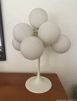 Full view of lamp showing white enamel tulip-style base and nine frosted globes